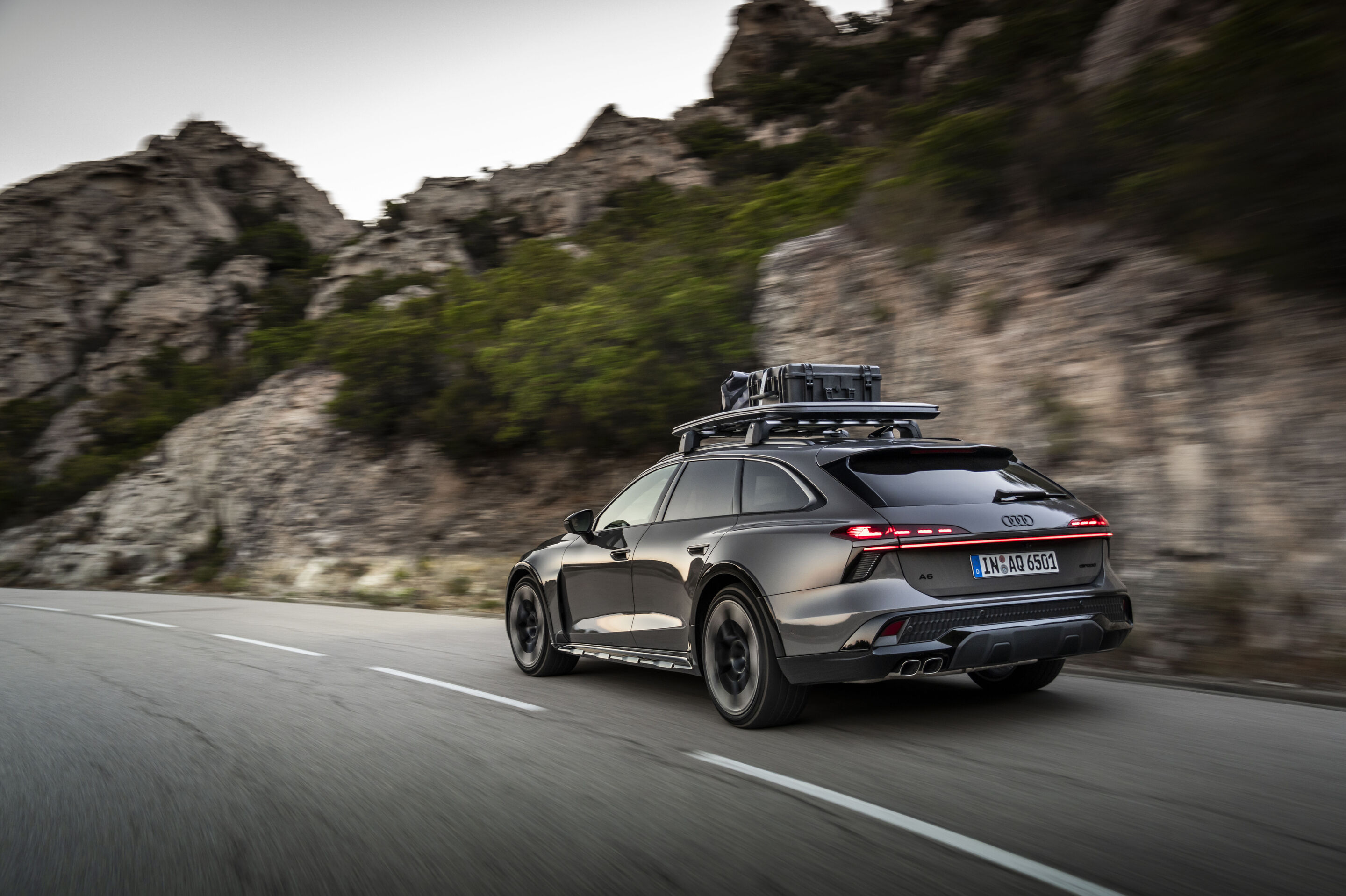 Audi A6 allroad TDI in Plateau Gray Metallic - Audi A6 allroad TDI in Plateau Gray Metallic with roof box, outdoor driving shot, exterior, three-quarter rear view in a mountainous landscape.