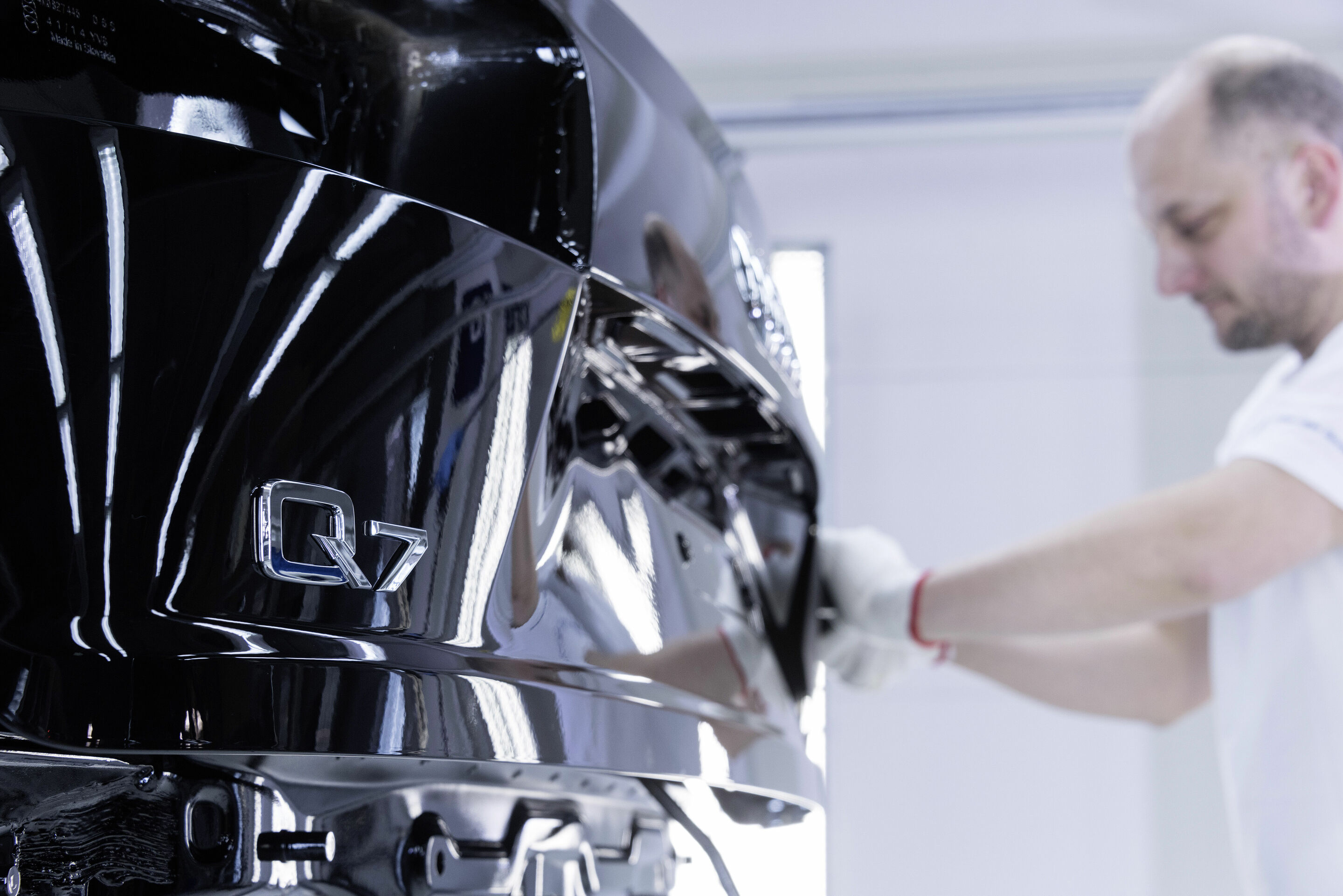 Audi Bratislava - Bevor die lackierte Karosse in die Montage geht, bringen Mitarbeiter am Heck des Audi Q7 die Typbezeichnung an.