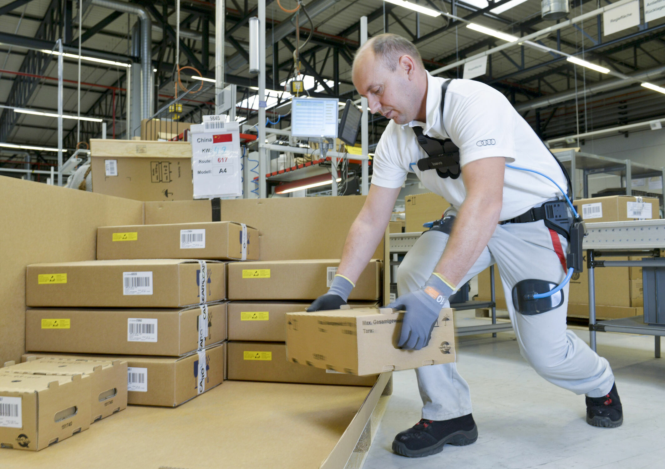 Audi production: working without backache with the exoskeleton - The ergonomic aid supports employees in production and logistics when lifting and carrying heavy materials. An Audi employee uses the exoskeleton when packing car components in CKD (completely...