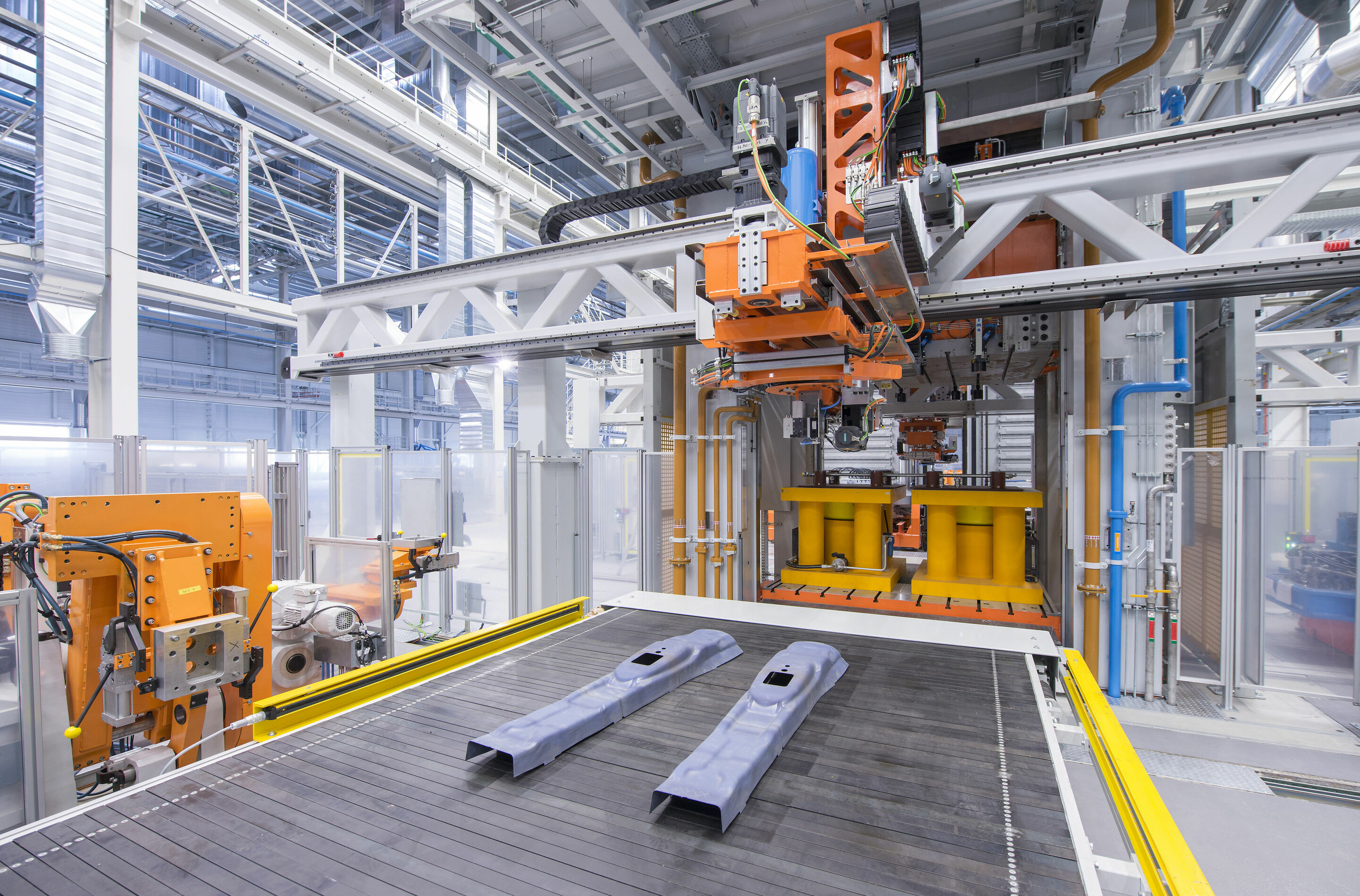 Audi Fertigung Münchsmünster – Presswerk - Das Auslaufband mit den fertig gepressten Halbteilen, Entnahme des Halbteiles aus der Presse durch den Feeder und Ablegen auf dem Auslaufband.
